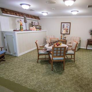 A cozy dining area with a table, surrounded by chairs and decorated with plants and artwork.