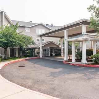 The entrance of a residential or commercial building with a driveway and surrounding greenery.