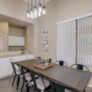 A modern dining room with a minimalist design, featuring a large table and several chairs under contemporary lighting.