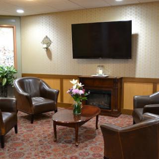 A cozy lounge area featuring comfortable seating, a television, and decorative flowers.
