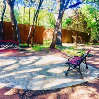A peaceful garden setting with benches under the shade of trees.