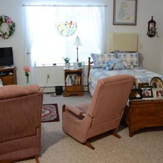 A cozy living room with armchairs, a bed, TV, and decorative elements.