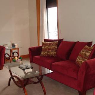 A cozy living room featuring a red sofa with patterned cushions and a glass coffee table.