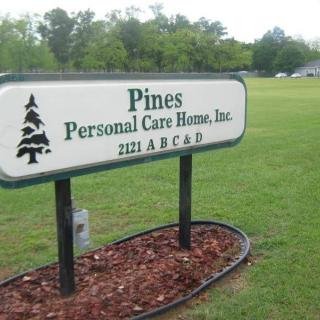 Sign for Pines Personal Care Home, Inc. set against a grassy lawn.