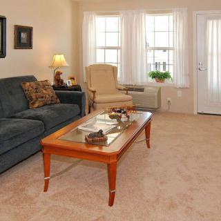 A cozy living room with a sofa, coffee table, armchair, and large windows.