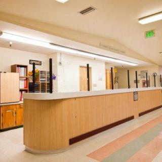 A hospital reception area with a desk and corridor.