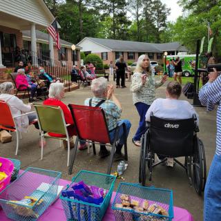A lively outdoor gathering with people seated in chairs and socializing, featuring a festive atmosphere.
