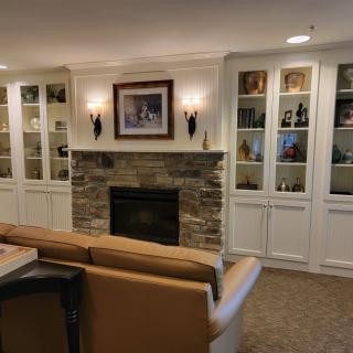 A cozy living room with a central fireplace, flanked by built-in bookshelves and illuminated by wall sconces.