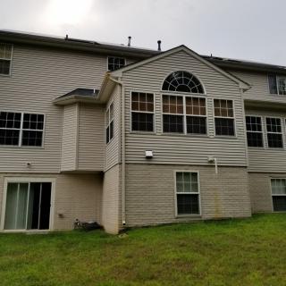A view of a residential house with large windows and a grassy backyard.