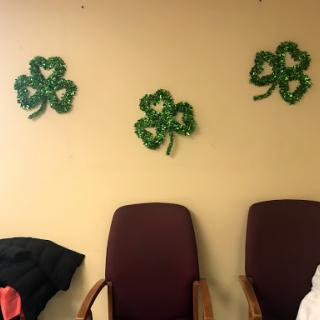 Decorative shamrocks adorn the wall above empty chairs.