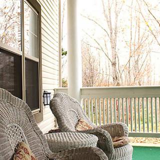 A cozy porch with wicker chairs overlooking a tranquil yard.