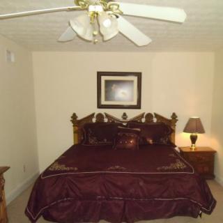 A traditional bedroom with a dark wood bed, matching nightstands, a ceiling fan, and a lamp.