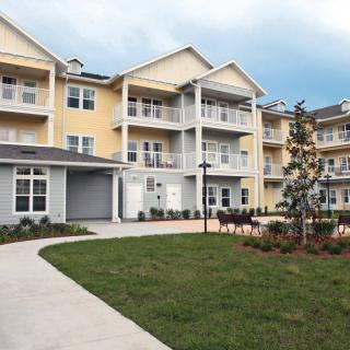 A modern multi-story apartment building with balconies and well-maintained landscaping.