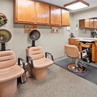 A cozy hair salon interior featuring salon chairs, hair dryers, and wooden cabinets.