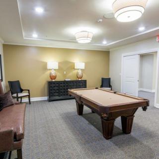 A stylish billiard room featuring a pool table, seating, and elegant lighting.
