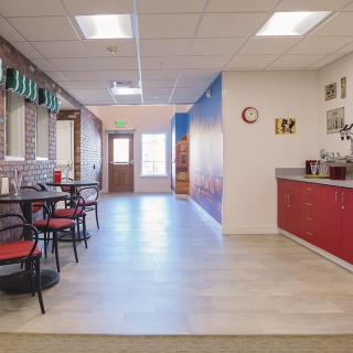 A modern cafeteria with red accents featuring tables and chairs, ample lighting, and a stylish decor.