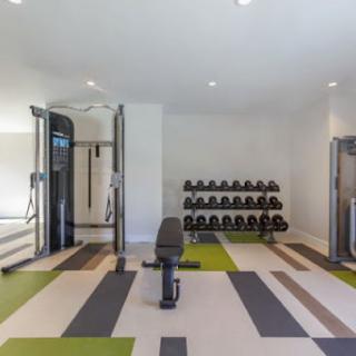 A modern indoor gym featuring a variety of exercise equipment, including dumbbells and a multi-functional machine.