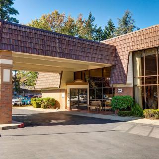 An exterior view of a building entrance with a covered driveway surrounded by trees.