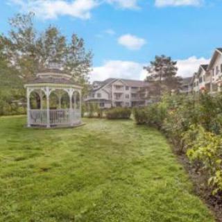A serene garden with a gazebo and residential buildings in the background.