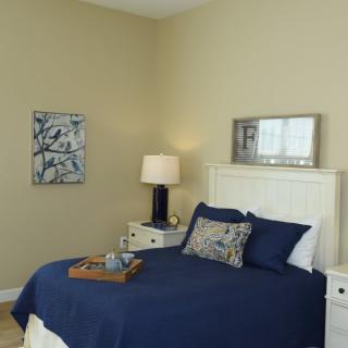 A modern bedroom with blue bedding, beige walls, and elegant decor.