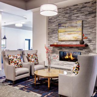 A modern living room with a cozy fireplace, stylish armchairs, and a wooden table in an elegant setting.