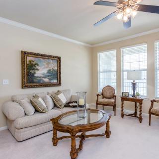 A cozy living room featuring a plush sofa, glass coffee table, and elegant decor with large windows allowing natural light.