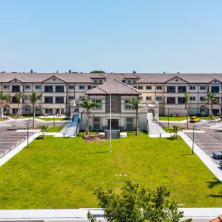 A modern apartment complex with manicured lawns and palm trees on a clear day.