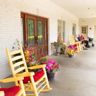 A charming front porch with bright rocking chairs and colorful flowers.