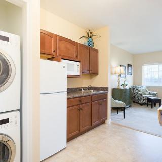 A cozy apartment interior featuring a compact kitchen with appliances and an adjoining living area.