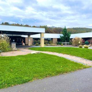 A modern building set amidst a well-maintained lawn, with pathways leading up to it.