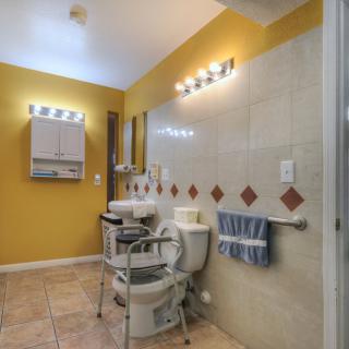 A well-lit bathroom with yellow walls, a large mirror, and tiled flooring.