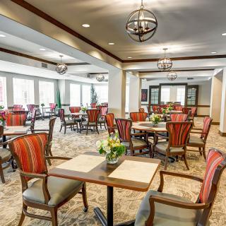 A well-lit and elegantly decorated dining area with several tables and chairs arranged neatly.