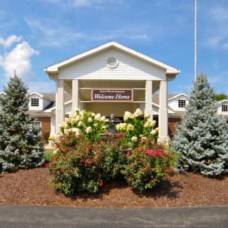 A well-maintained building entrance with lush landscaping and clear blue sky.
