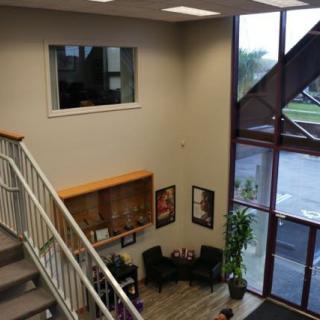 A modern office lobby featuring a staircase, seating area, and large windows.