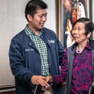 A healthcare professional interacting with an elderly person, offering support and care.