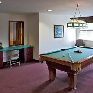 A cozy game room featuring a pool table with cues and balls ready for play.
