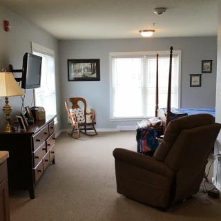 A cozy living room with a recliner, television, and rocking chair by the window.