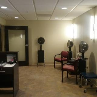 A cozy waiting area in a modern salon, featuring chairs and hairdryers.