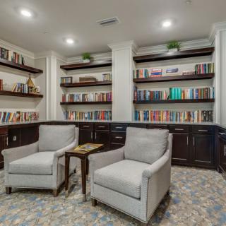 A cozy library with armchairs and bookshelves lined with books.