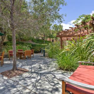 A serene outdoor patio surrounded by lush greenery and comfortable seating.