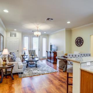 A cozy living room with stylish furniture and hardwood flooring, featuring a sofa, coffee table, and elegant lighting.