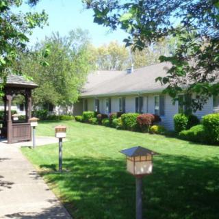 A peaceful residential area with a well-maintained lawn, trees, and a small gazebo.