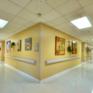 A brightly lit hospital hallway featuring artwork on the walls.