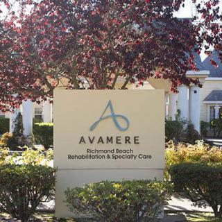 A sign for Avamere Post-Acute Rehab, set against a backdrop of trees and greenery.