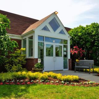 A charming building entrance surrounded by lush greenery and colorful flowers.