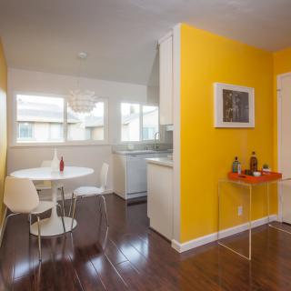 Modern kitchen and dining area with yellow accent walls and a round table.