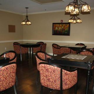 A cozy game room with tables, chairs, and a chess board under warm lighting.