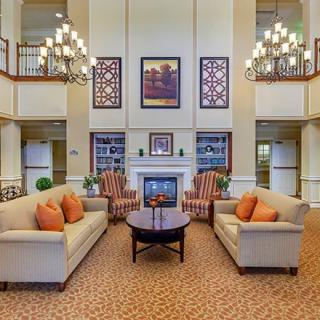 A luxurious living room with elegant chandeliers and comfortable seating arrangements centered around a fireplace.