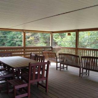 A covered porch with wooden furniture overlooking a lush green view.