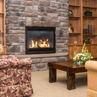 A cozy living room featuring a stone fireplace, comfortable seating, and wooden shelves.